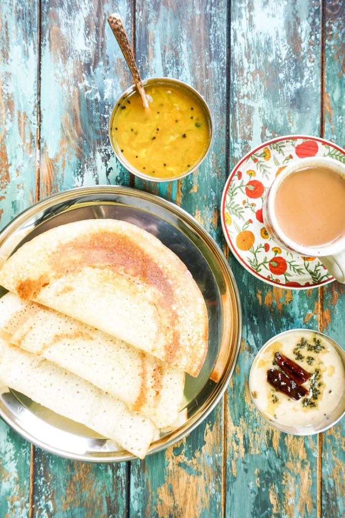 dosas on a plate with a cup of chai next to it