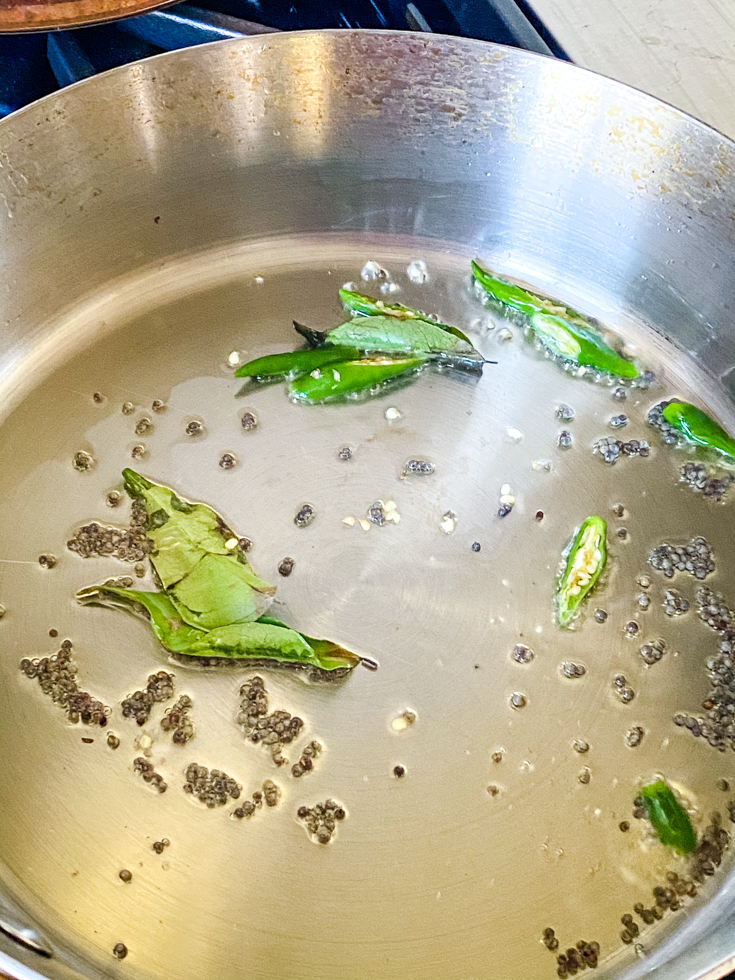 mustard seeds and curry leaves in oil in a saute pan