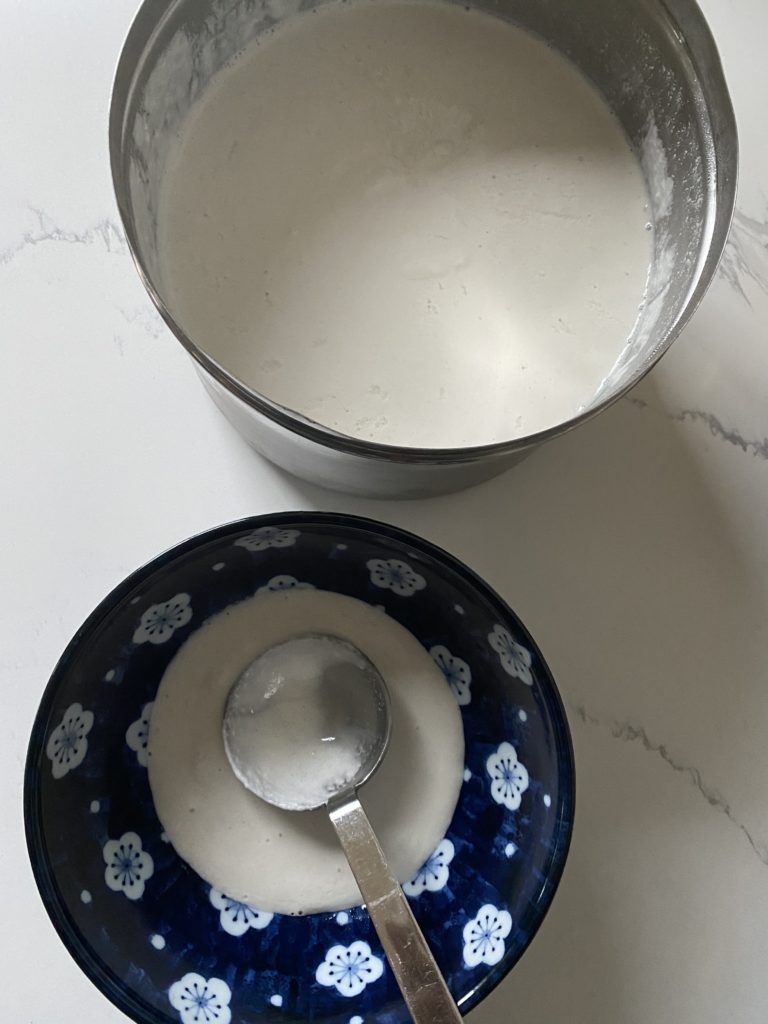 A large container and a small bowl with dosa batter in them