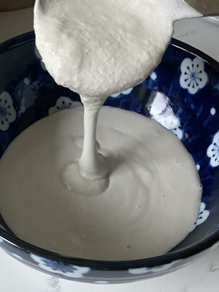 ladle pouring dosa batter in to a bowl