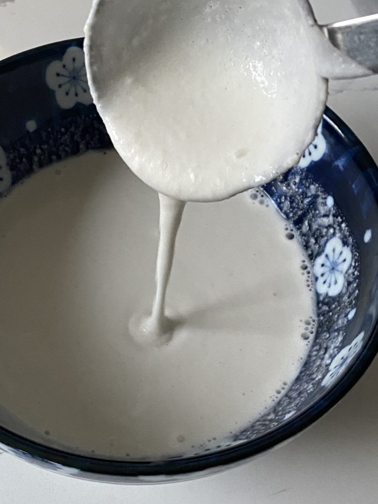 ladle pouring dosa batter in to a bowl