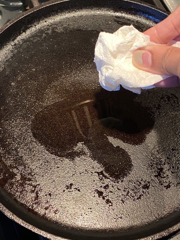 hand holding paper towel over a griddle