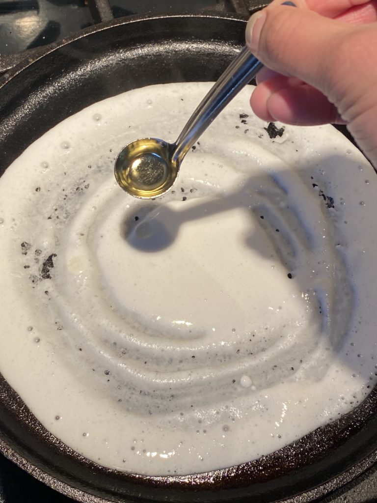 oil being poured on the dosa on a griddle