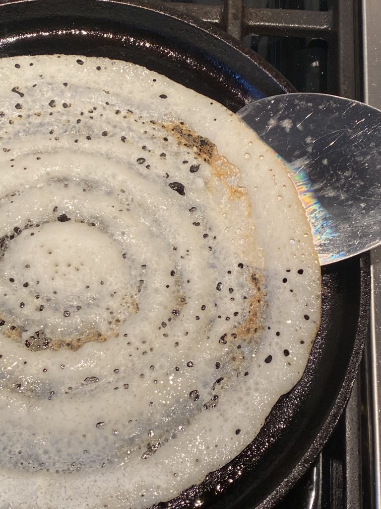 crispy dosa about the be flipped in the griddle