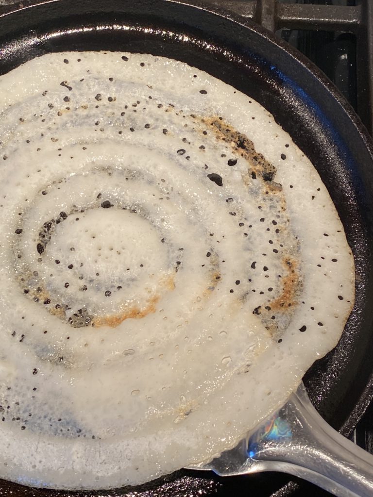 crispy dosa about the be flipped in the griddle