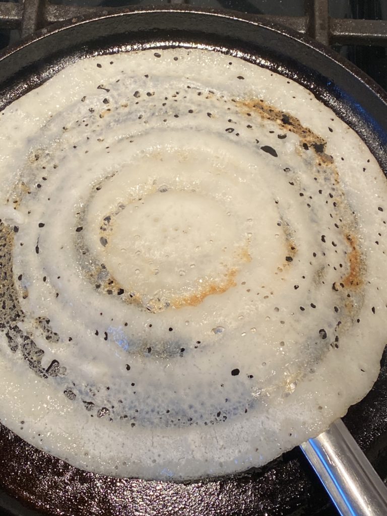 crispy dosa about to be flipped on the griddle