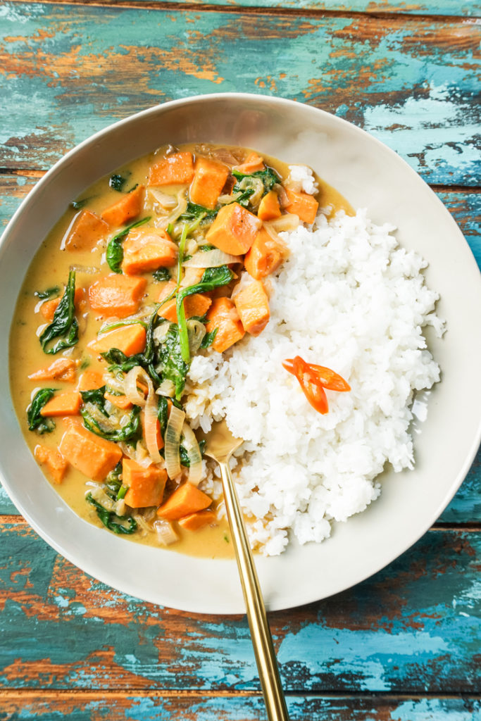 Thai sweet potato curry and white rice in a bowl with a gold fork