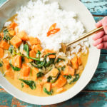 Thai sweet potato curry and white rice in a bowl with a gold fork