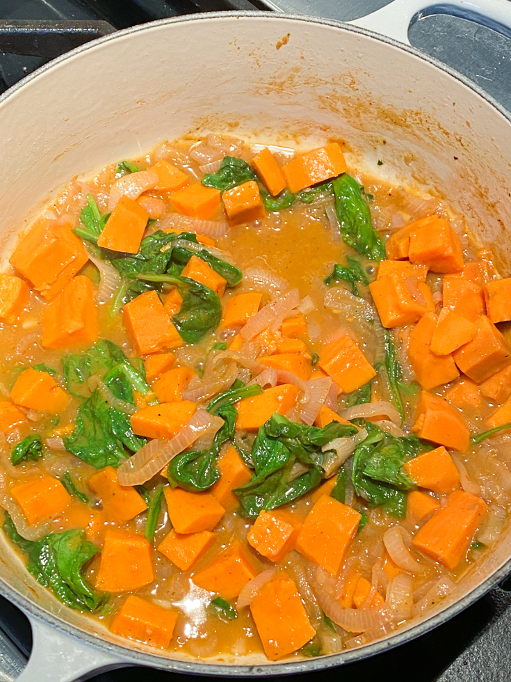 cooked sweet potatoes and spinach in a Dutch oven