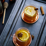 two glass cups on brass coasters with hot toddy