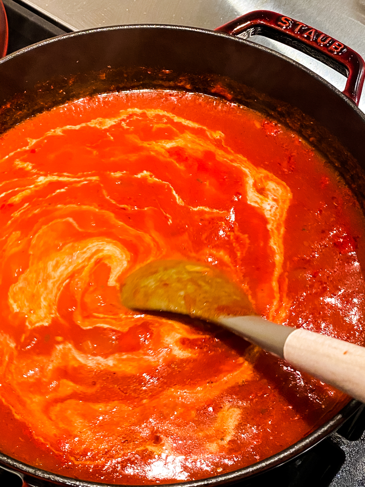 ladle stirring cream into the tomato soup in a Dutch oven