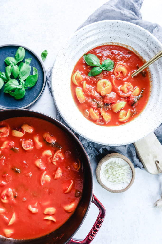 tomato basil tortellini soup in a bowl and Dutch oven