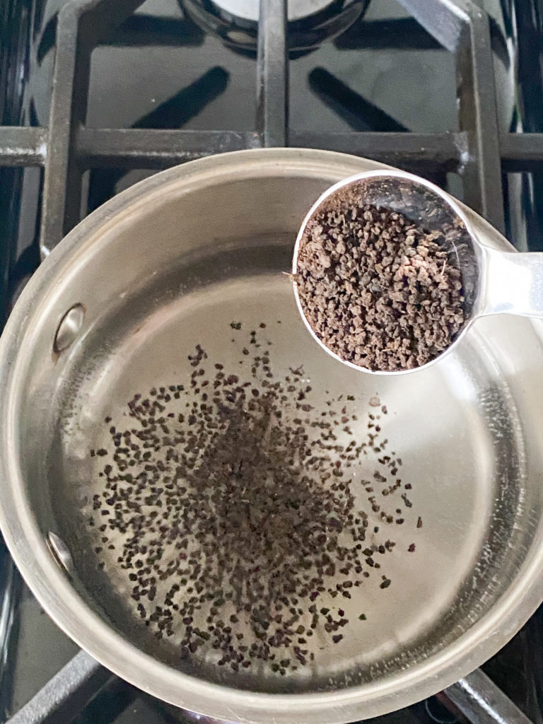 tea leaves being added to water in a saucepan