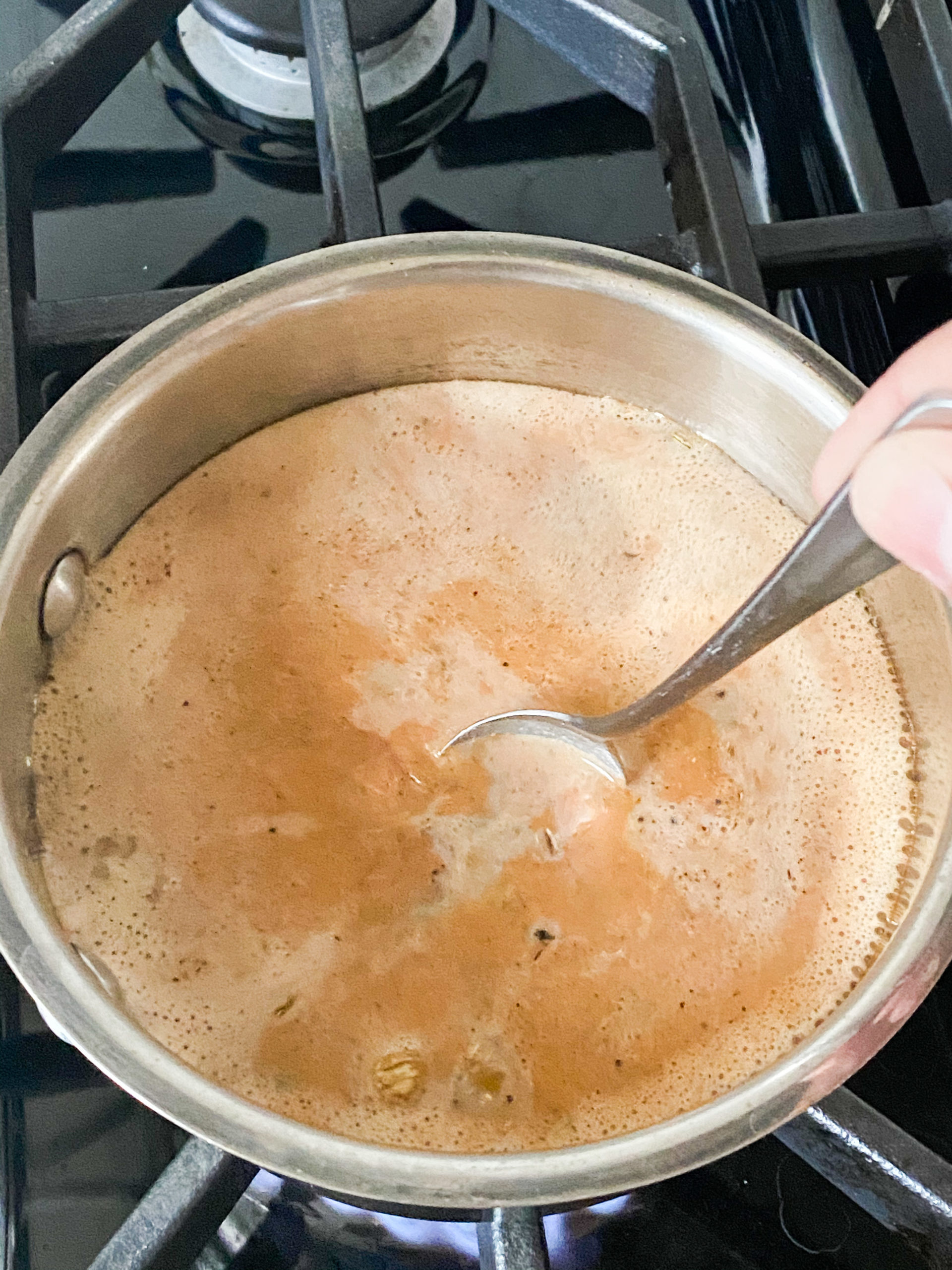 spoon stirring Indian chai in a saucepan