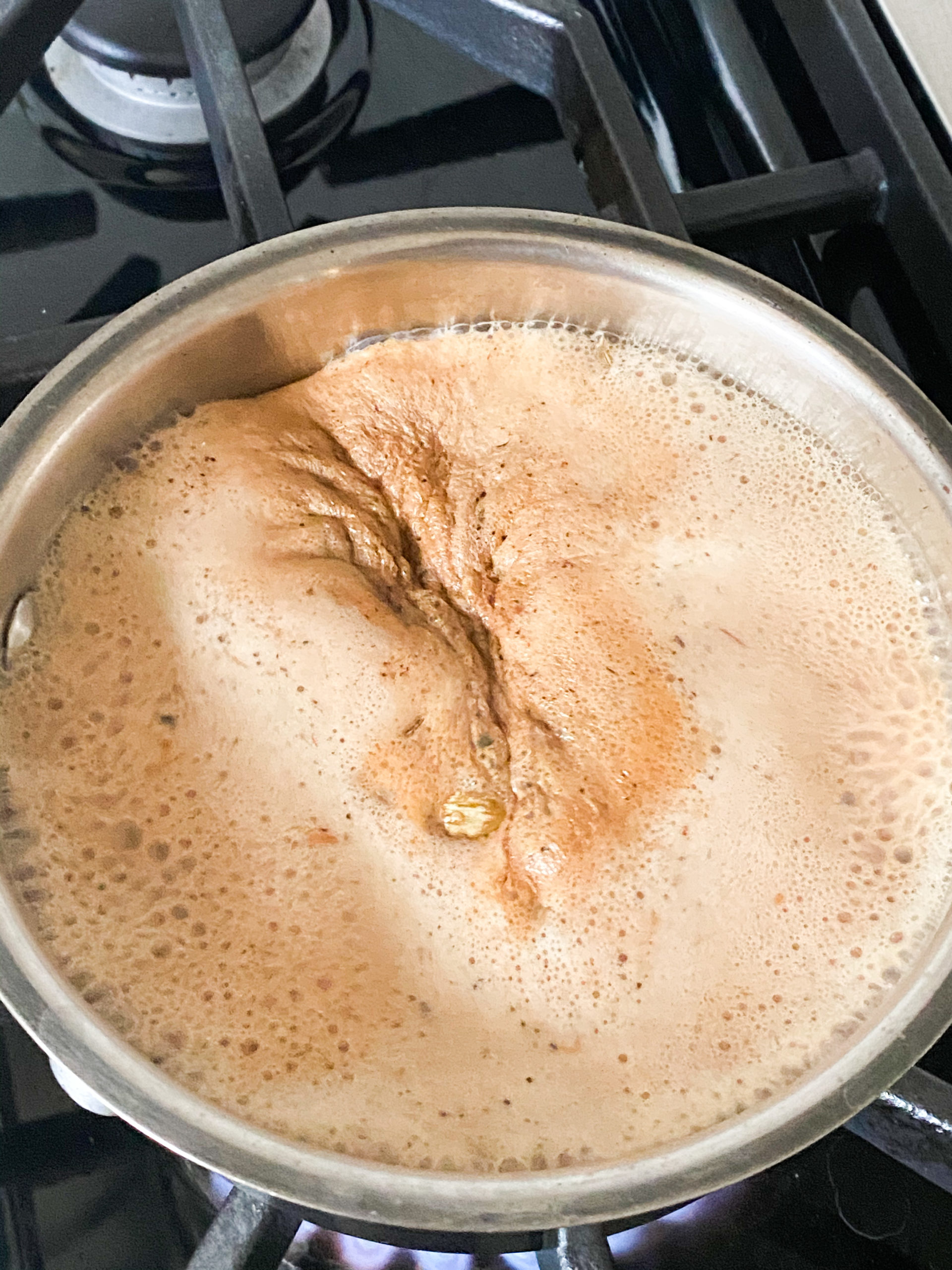 Indian chai with milk boiling in a saucepan