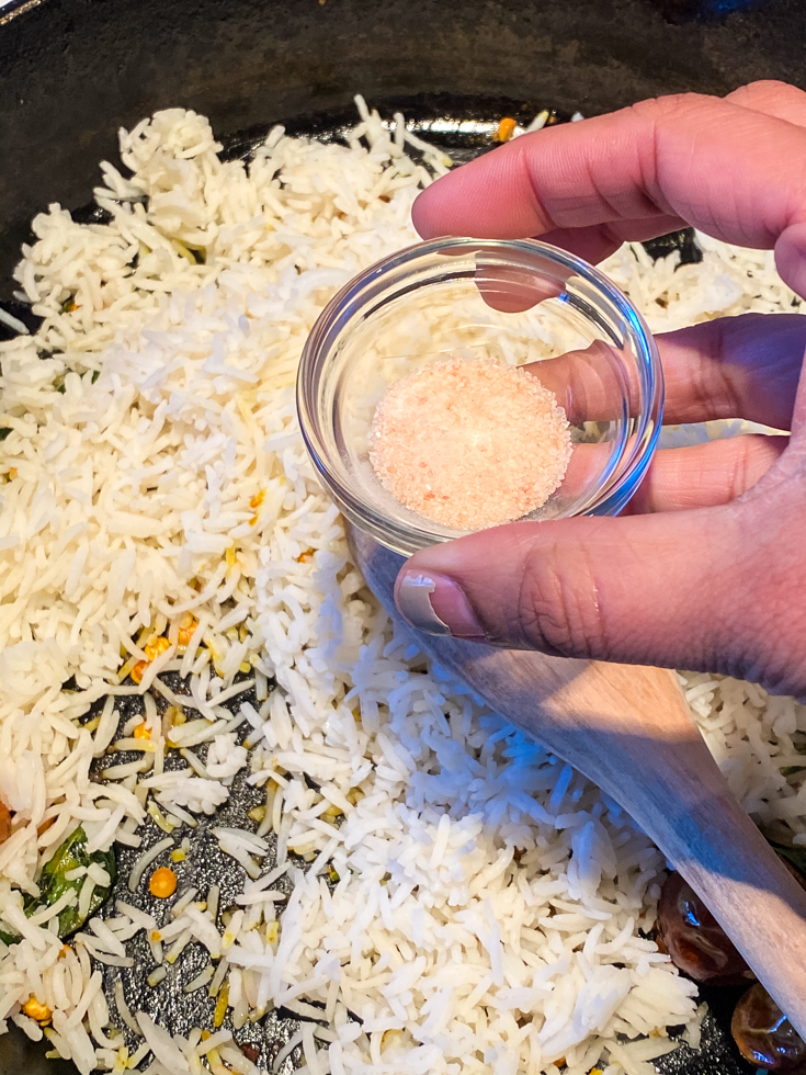 salt added to rice in a skillet