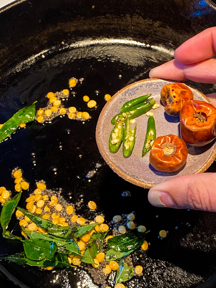 chillies being added to a skillet