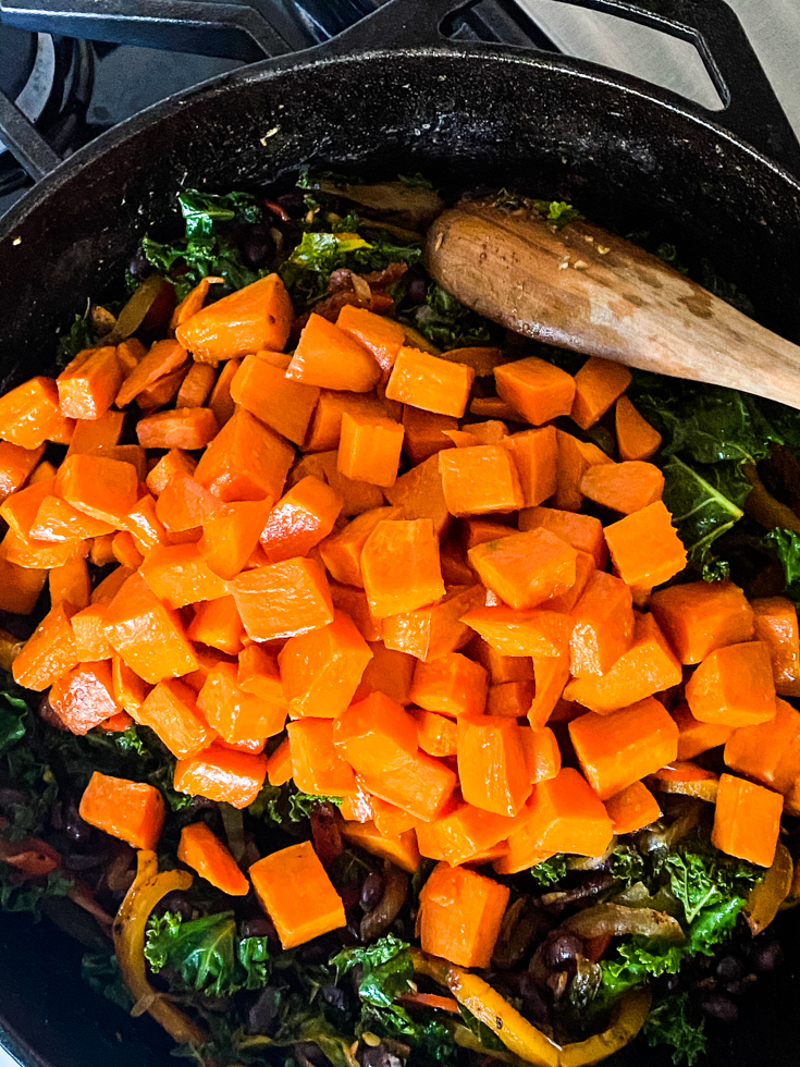 sweet potatoes added to skillet with kale and beans in it