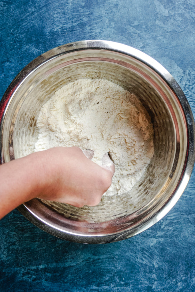 hand mixing murukku ingredients in a bowl