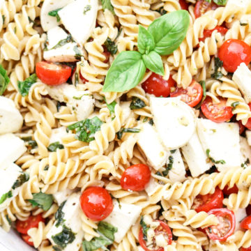 close up shot of caprese pasta salad in a white bowl