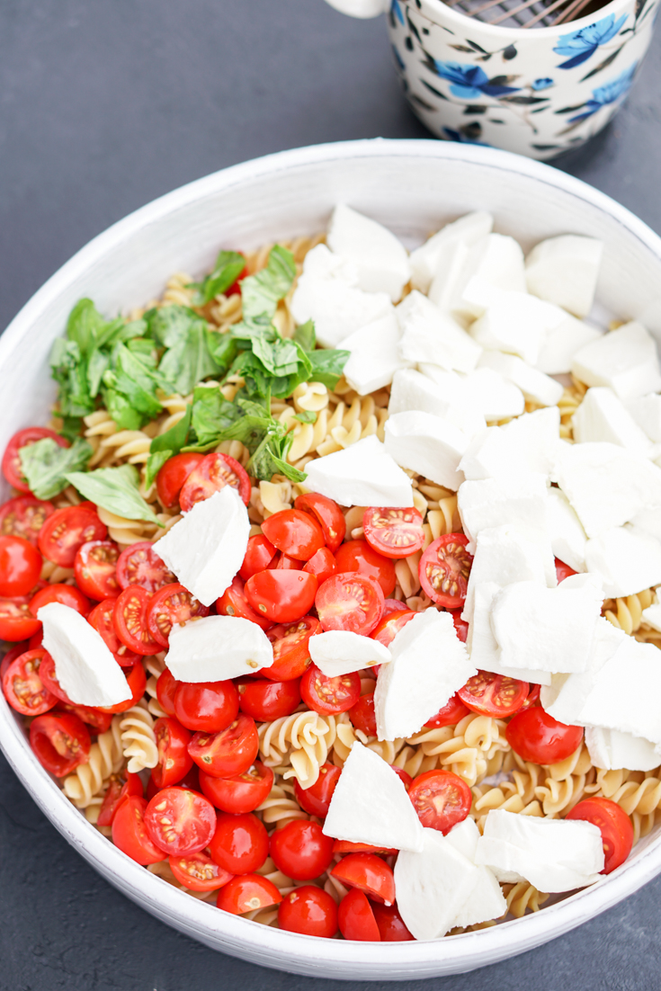 pasta, tomatoes, mozzarella and basil in a white bowl