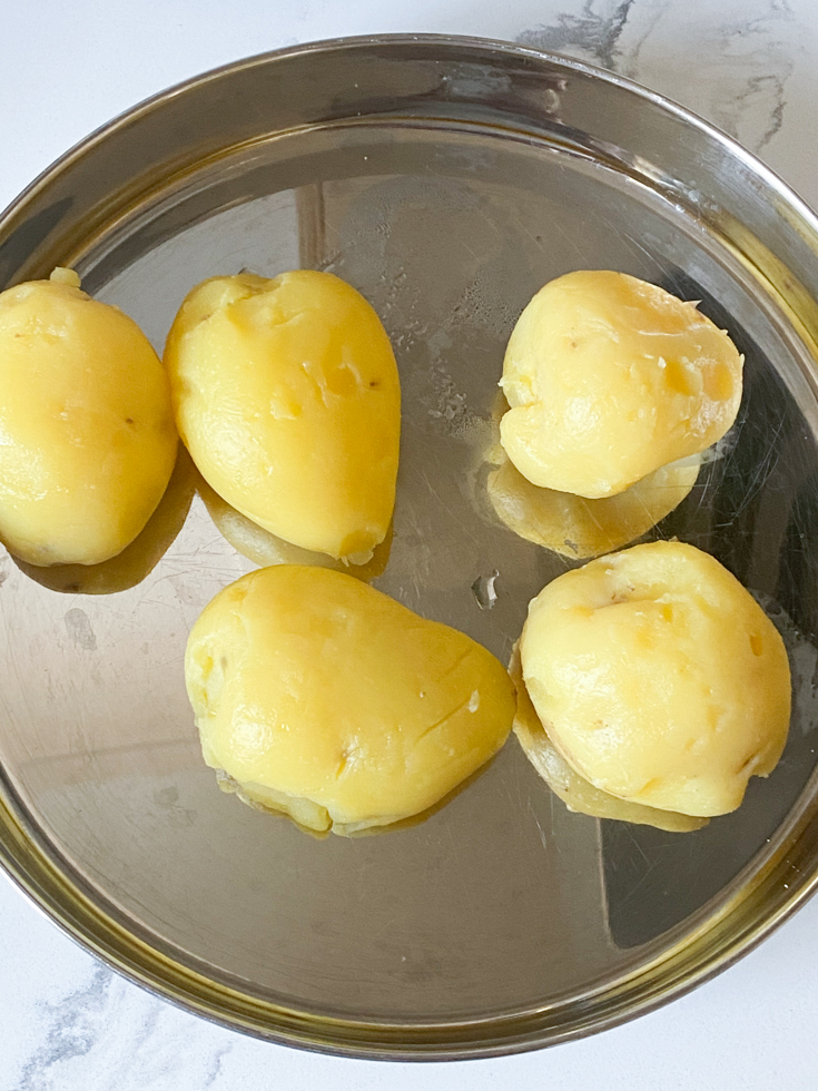 cooked and peeled potatoes in a stainless steel plate