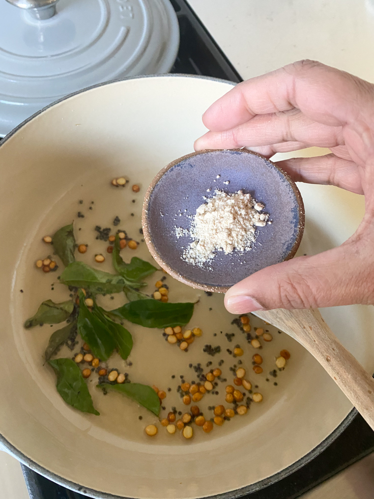 pinch bowl with asafetida powder about to be put in a pot