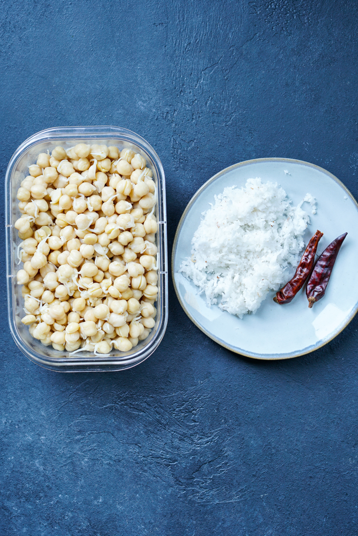 cooked chickpea sprouts in a plastic container and a plate with grated coconut and dried red chillies