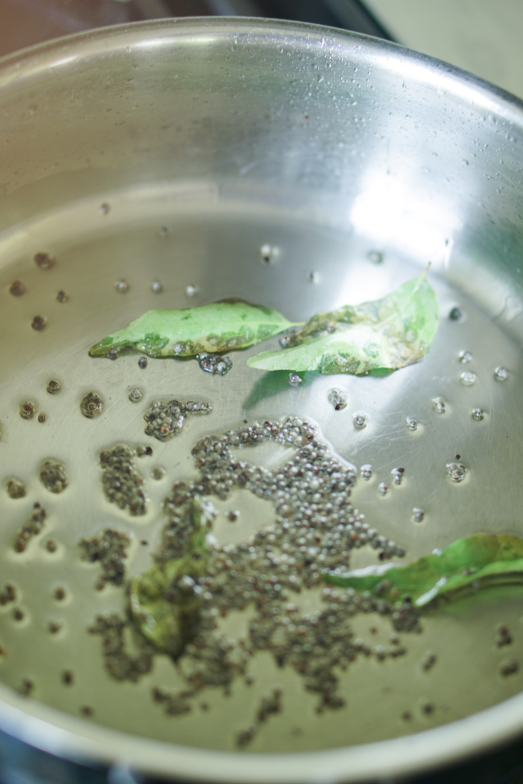 mustard seeds and curry leaves in oil in a saute pan