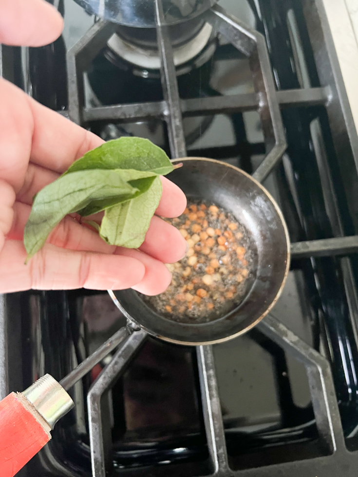 curry leaves in palm of hand ready to go in coconut oil