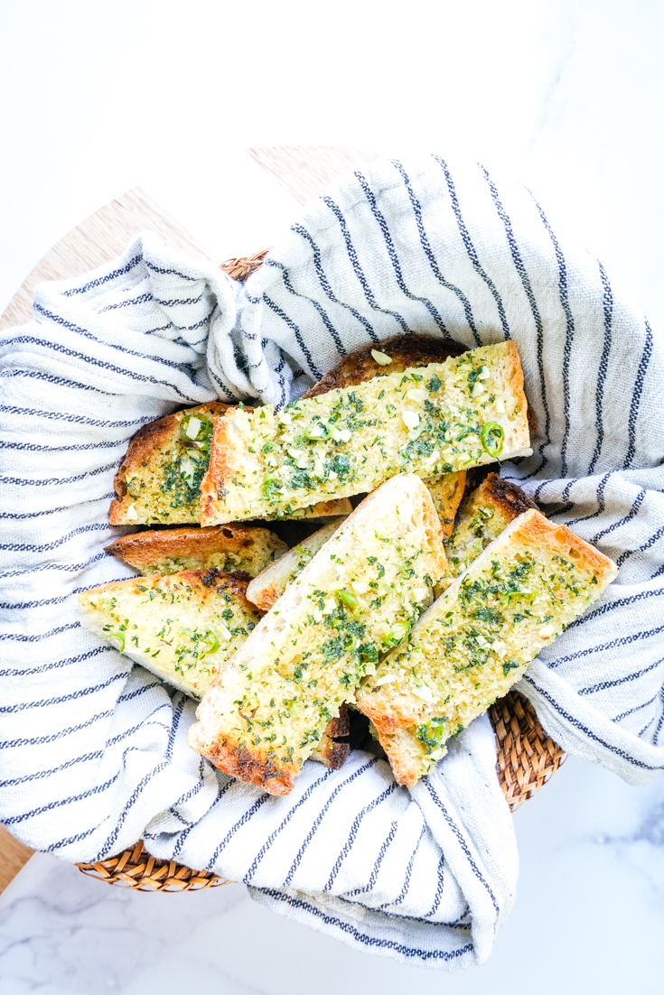 chilli garlic bread slices in a basket with a tea towel