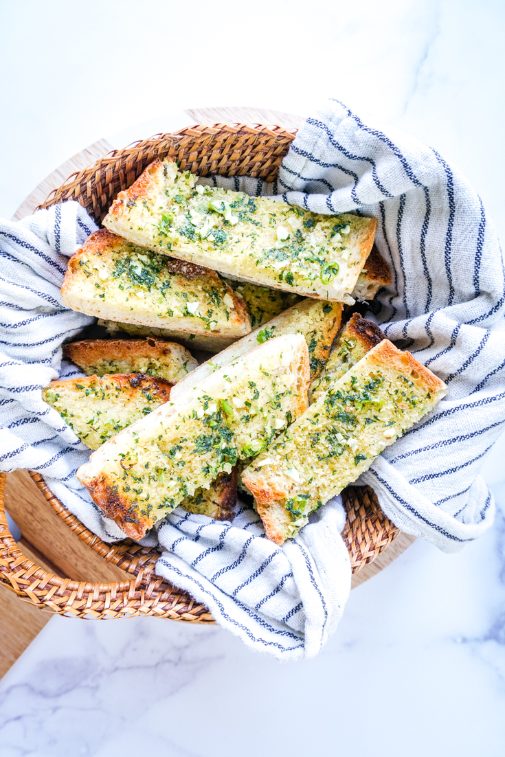 chilli garlic bread slices in a basket with a tea towel