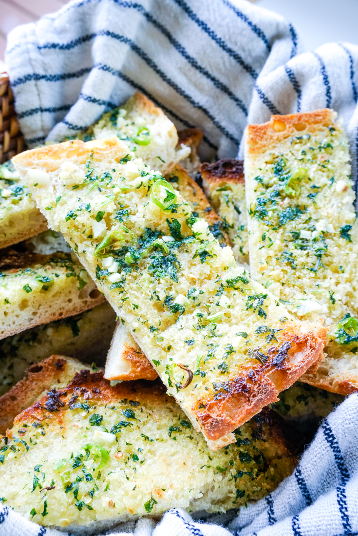 chilli garlic bread slices in a basket with a tea towel