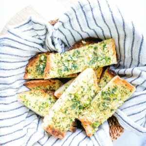 chilli garlic bread slices in a basket with a tea towel