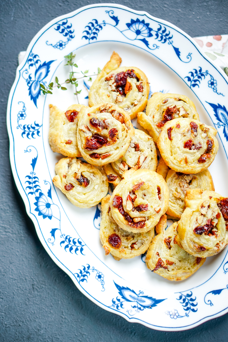 a blue and white platter full of cranberry brie pinwheels