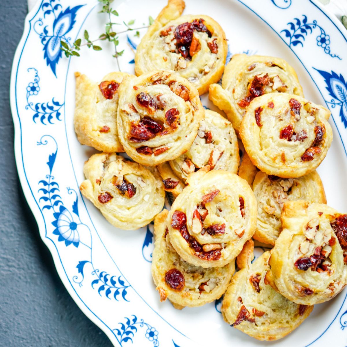 a blue and white platter full of cranberry brie pinwheels