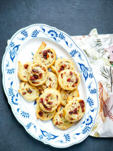 a blue and white platter full of cranberry brie pinwheels