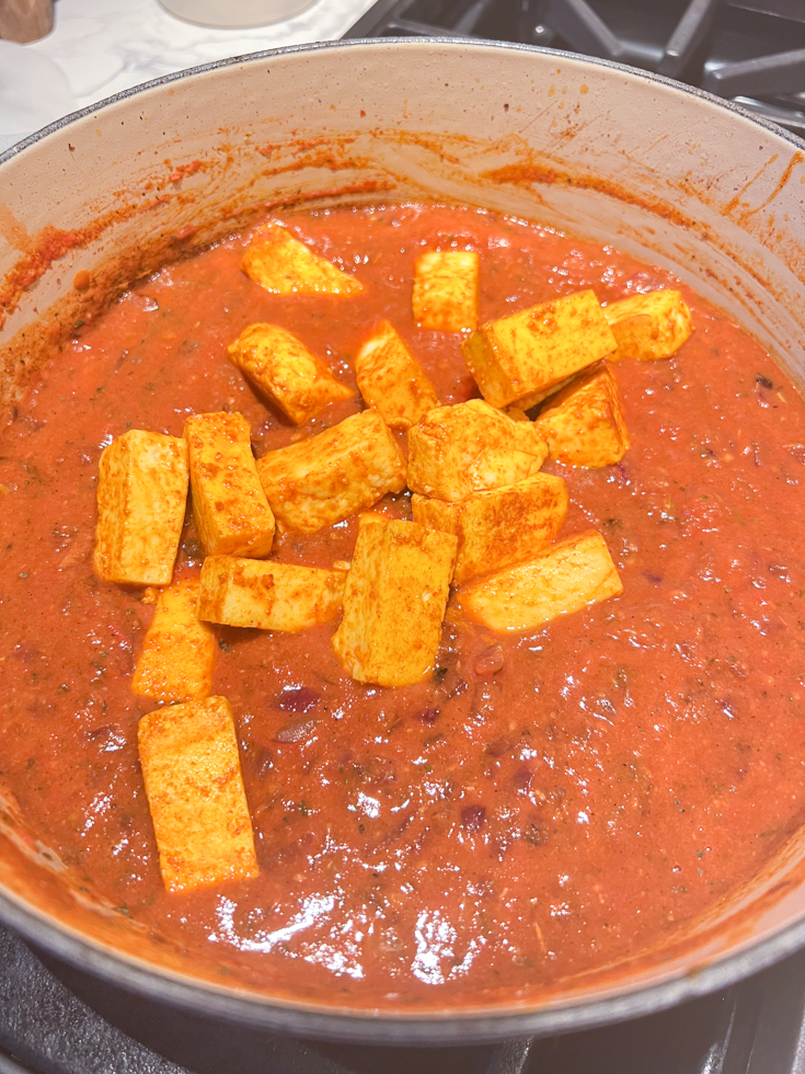 paneer added to the onion tomato sauce in a Dutch oven