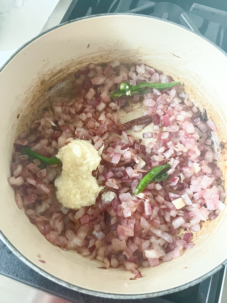 ginger garlic paste added to sauteed onions in a Dutch oven