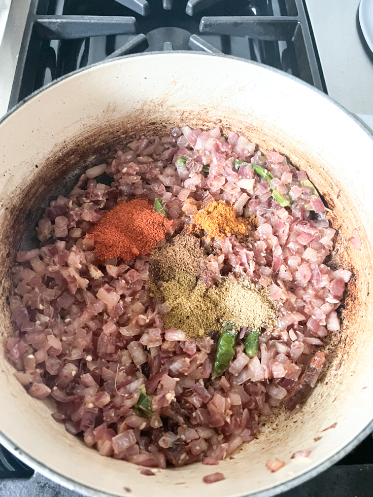 spices added to sauteed onions in a Dutch oven