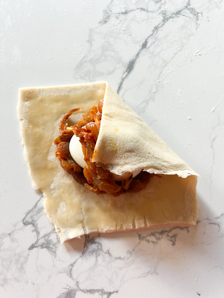 hand folding puff pastry to make egg puffs