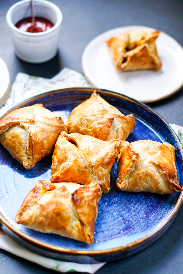 a blue plate of egg puffs and a cup of chai on the side