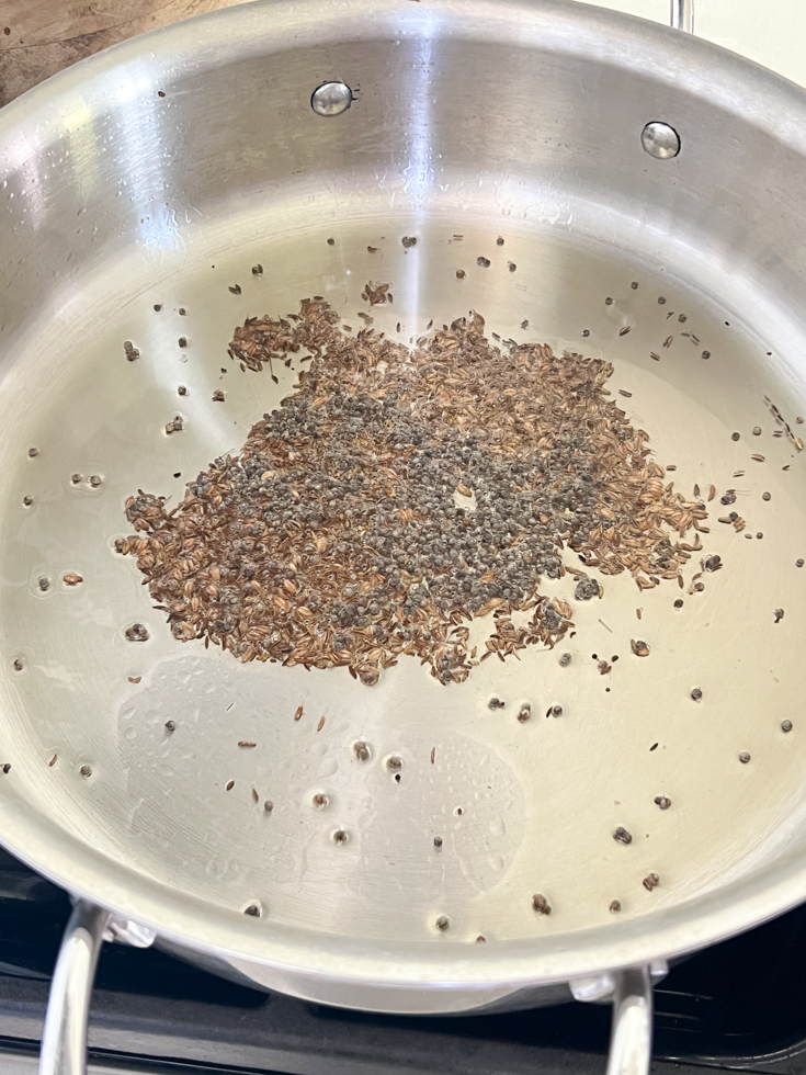 mustard seeds and cumin in hot oil in a stainless steel pan