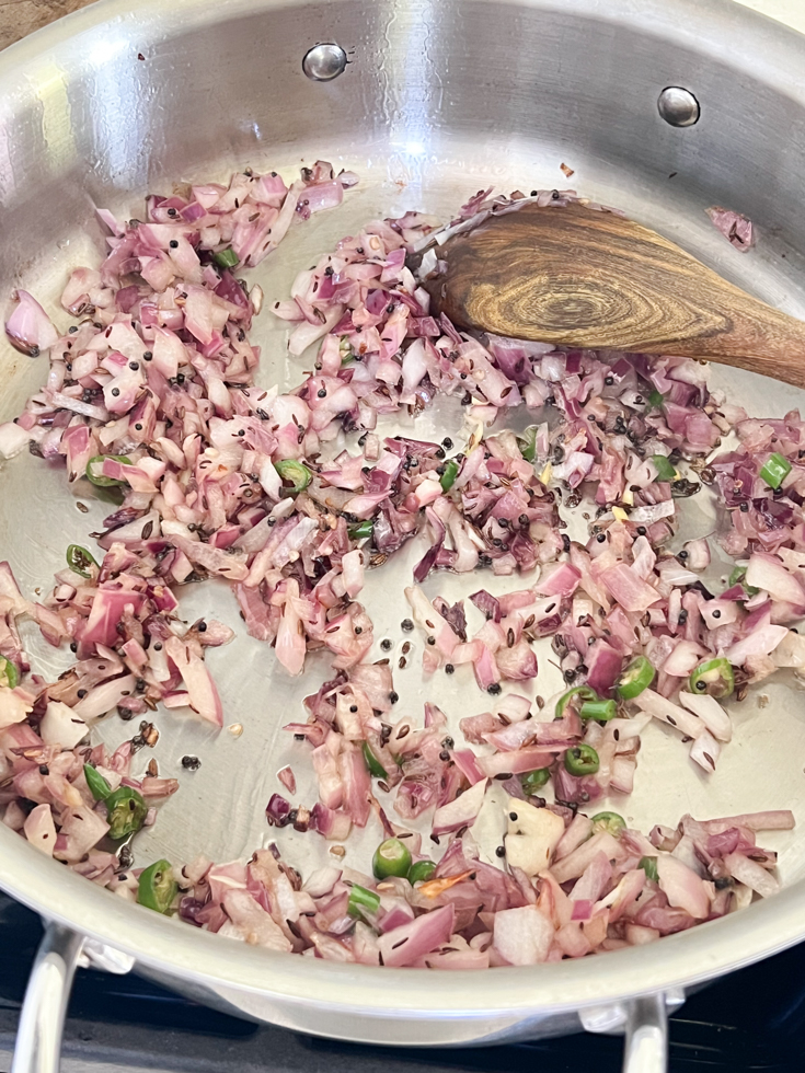 onions sautéing in a stainless steel pan