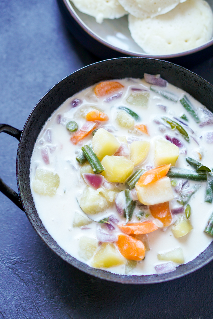 Stew with potato, carrot and green beans in coconut milk in a black kadai bowl