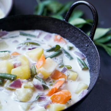 Stew with potato, carrot and green beans in coconut milk in a black kadai bowl
