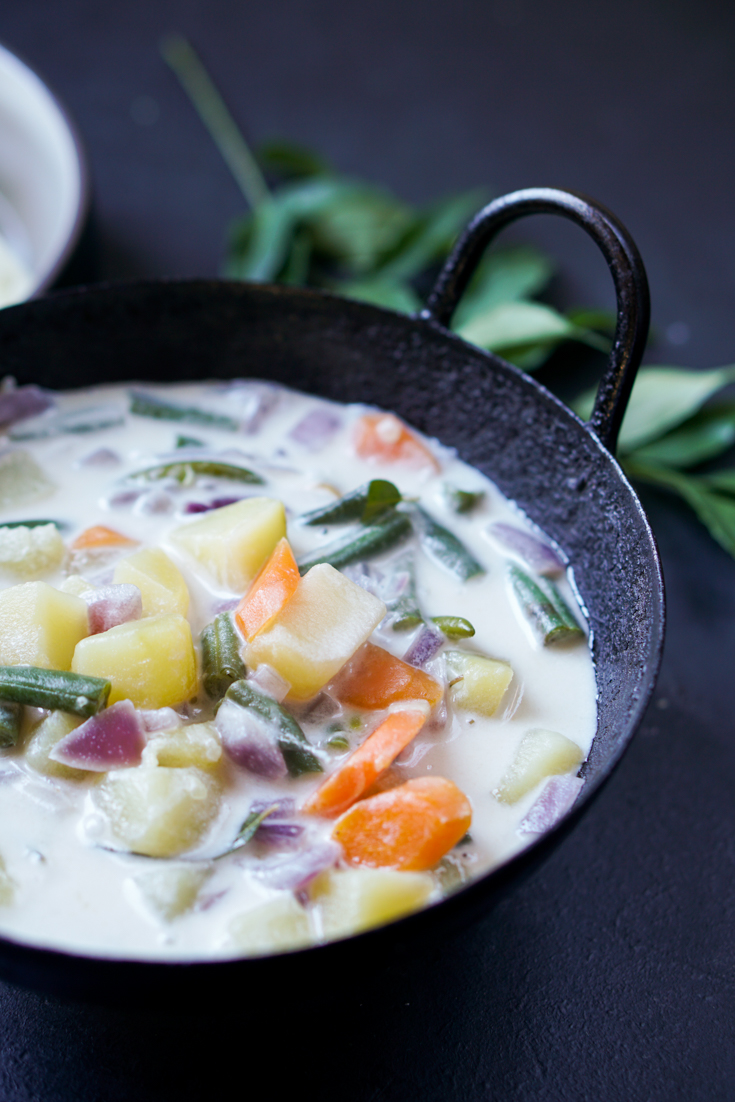 Stew with potato, carrot and green beans in coconut milk in a black kadai bowl