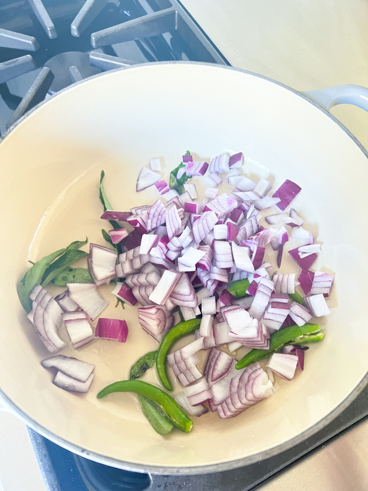 red onion, curry leaves and green chillies in Dutch oven