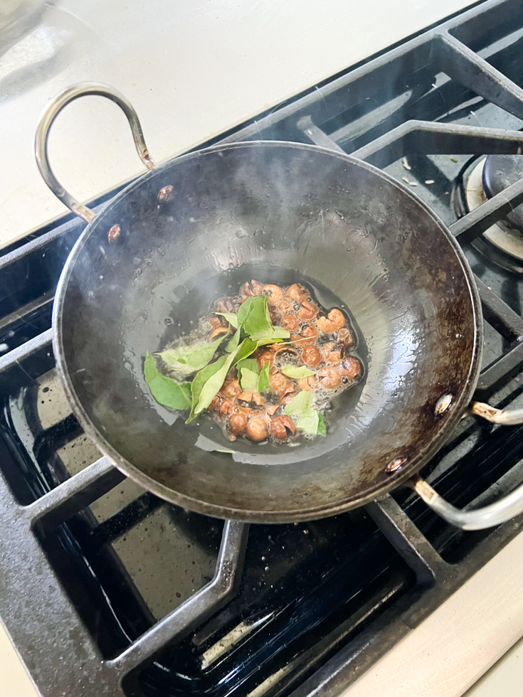 curry leaves and turkey berries in hot oil in a black pan