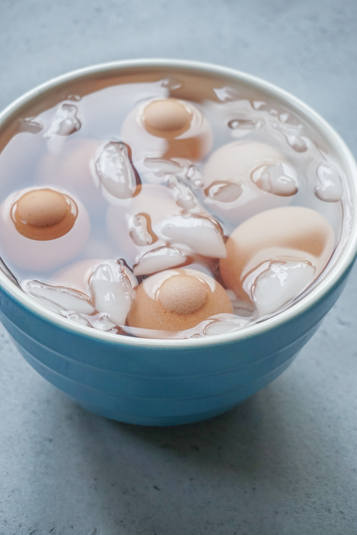 Eggs cooling in an ice water bath in a large bowl